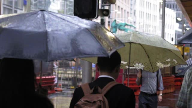 慢镜头:季风期间，人们撑着雨伞在城市里行走——澳大利亚悉尼视频素材