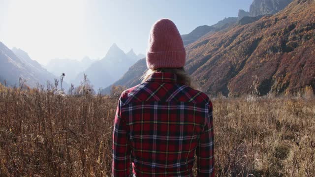 在秋日的群山中漫步的年轻女子。高山快乐游客视频素材