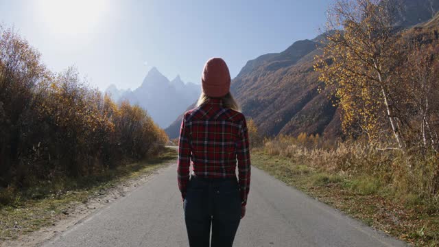 在秋日的群山中漫步的年轻女子。高山快乐游客视频素材