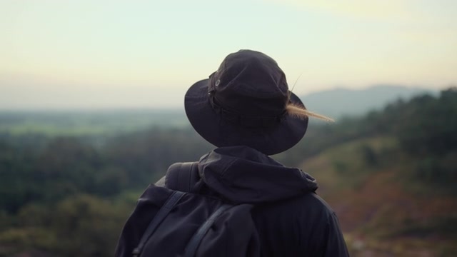 一个嬉皮士站在山顶眺望日落。视频素材画面1