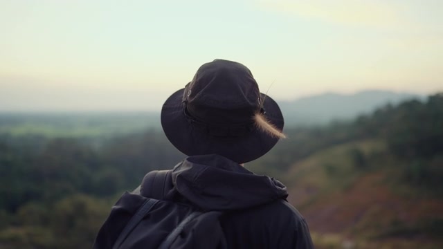 一个嬉皮士站在山顶眺望日落。视频素材画面2