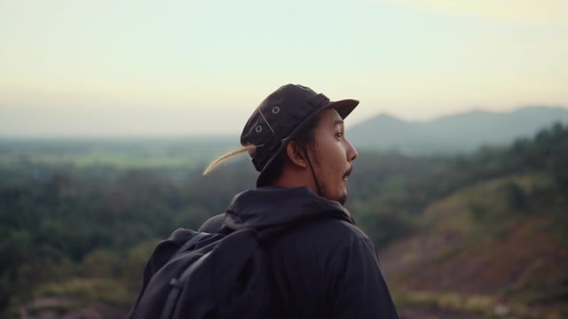一个嬉皮士站在山顶眺望日落。视频素材画面4