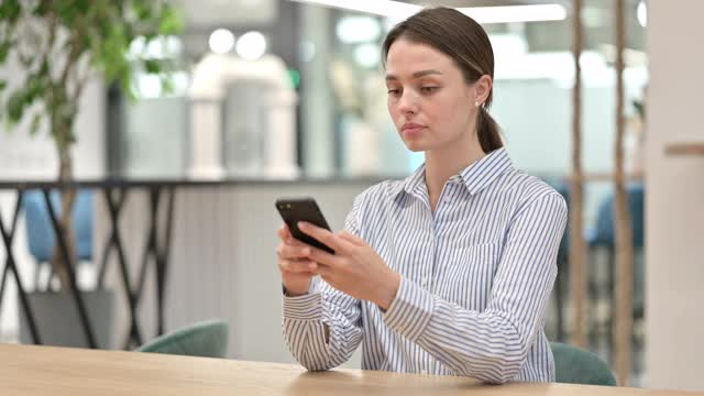 年轻漂亮的女人在办公室用智能手机聊天视频素材