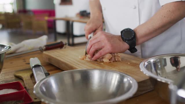 白人男厨师在厨房桌子上切肉视频素材