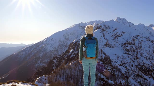 一位年轻的徒步旅行者站在山顶，双臂张开视频素材