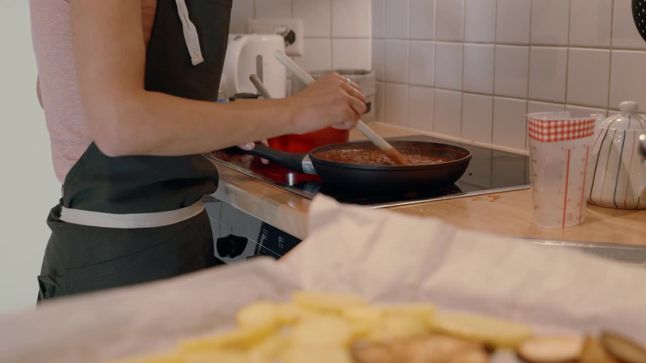 年轻女子在家里做美味的饭菜。在厨房里，一名女子在平底锅里搅拌准备食物视频素材