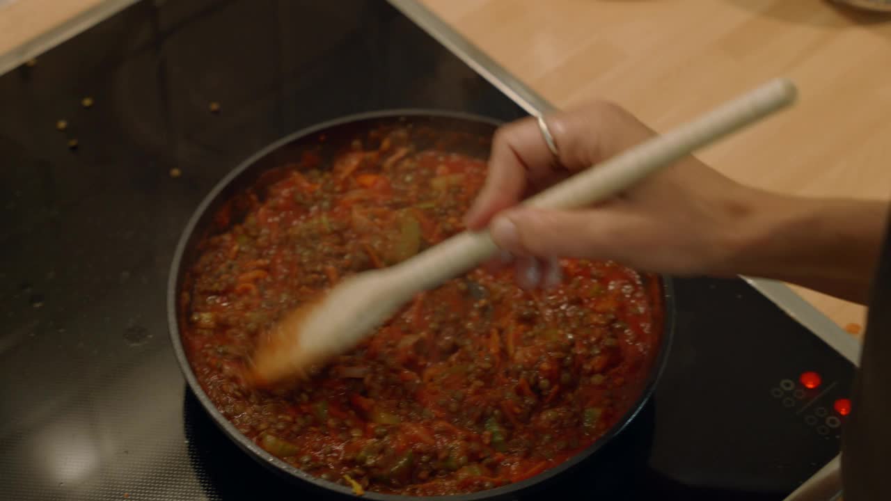 年轻女子在家里做美味的饭菜。在厨房里，一名女子在平底锅里搅拌准备食物视频素材