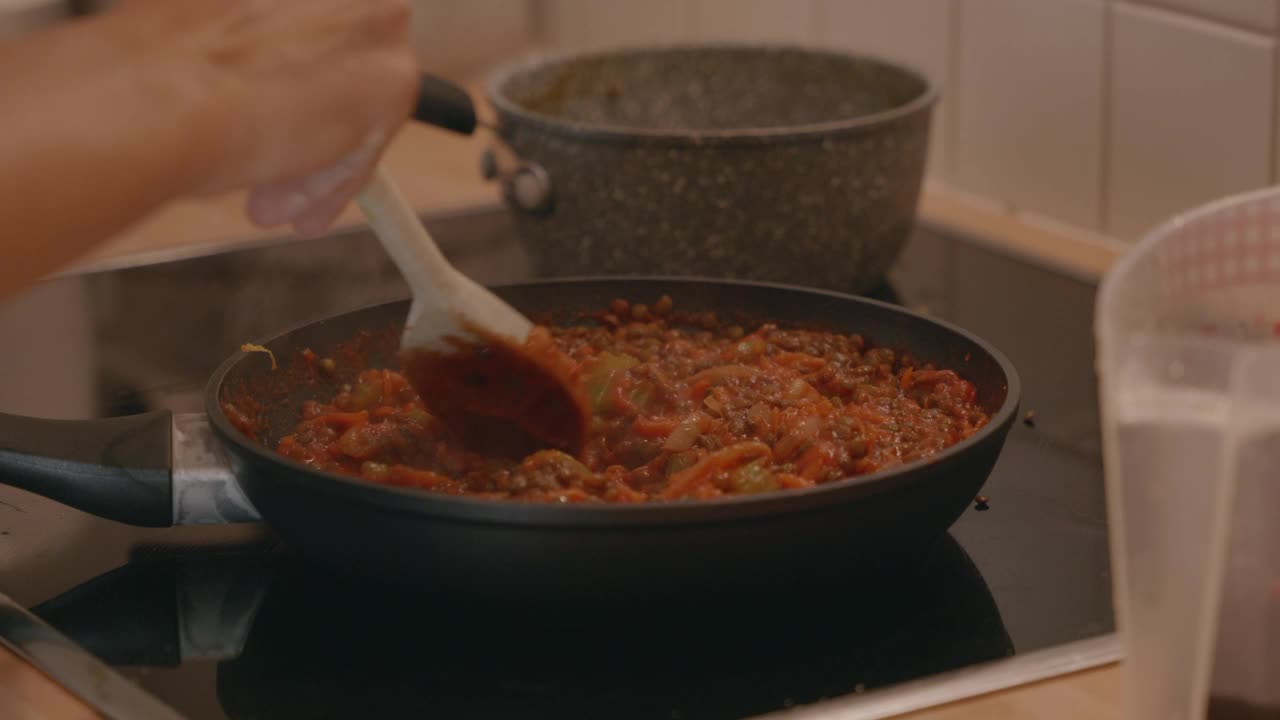 年轻女子在家里做美味的饭菜。在厨房里，一名女子在平底锅里搅拌准备食物视频素材