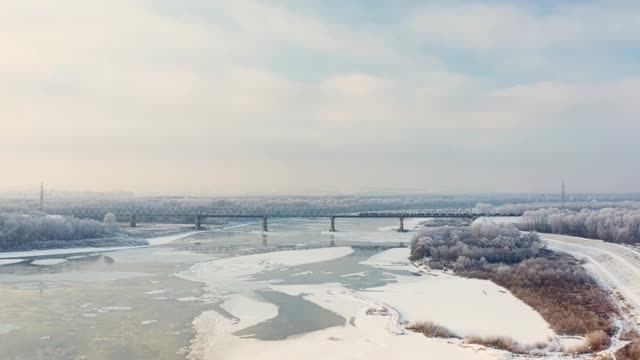 河上融化的冰的鸟瞰图。河堤旁白雪皑皑，用桥架空拍摄。视频素材