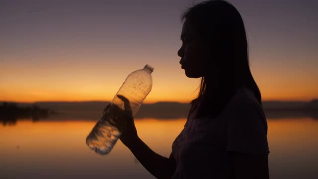 年轻女性在日落时喝水视频素材