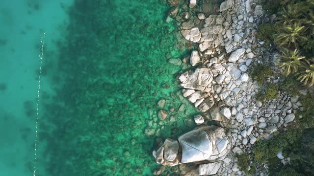 无人机俯瞰海洋和海滩上的岩石，Kho Tao岛泰国飞行在清澈的蓝色海水上方令人惊讶的低航拍海面。股票视频视频素材