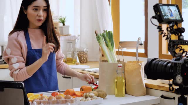 一名亚洲女子在摄像机前录制视频。用相机记录水果和健康饮料的故事给她的订户。视频素材