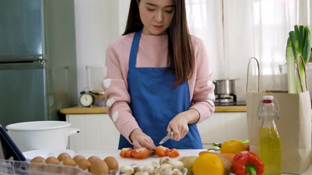 年轻的亚洲女性用平板电脑烹饪食谱视频素材