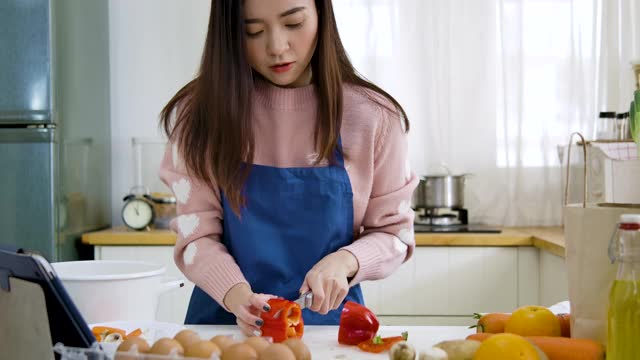 年轻的亚洲女性用平板电脑烹饪食谱视频素材