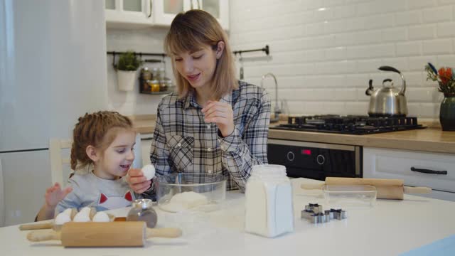 年轻的母亲和女儿一起在厨房里烤饼干视频素材