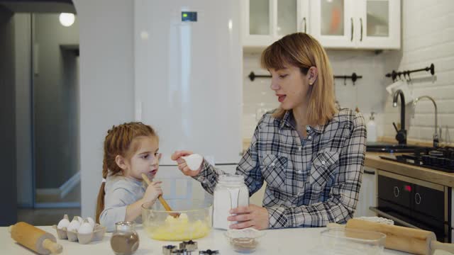 年轻的母亲和女儿一起在厨房里烤饼干视频素材