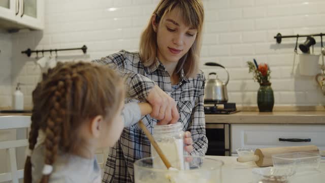 年轻的母亲和女儿一起在厨房里烤饼干视频素材