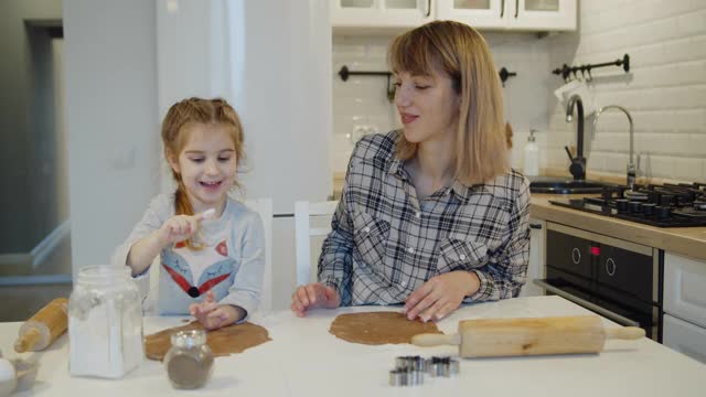 年轻的母亲和女儿一起在厨房里烤饼干视频素材