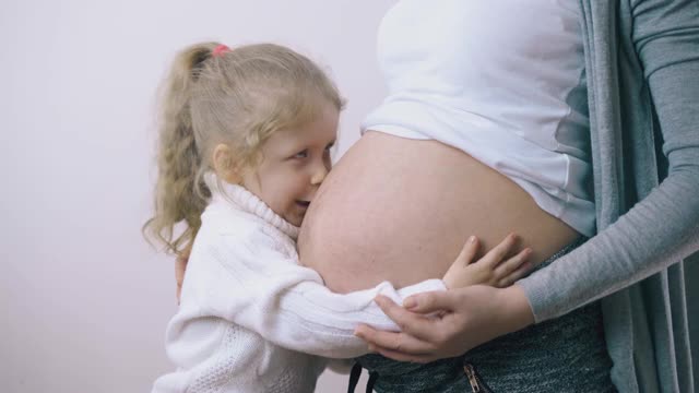 漂亮女孩在房间里抚摸着大肚子的孕妇视频素材