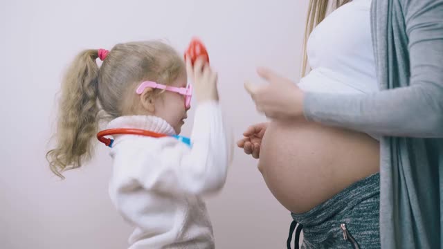 女孩用玩具听诊器摸孕妇的肚子视频素材