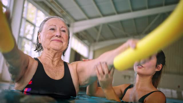 教练在健美操课上帮老女人养泳池面视频素材