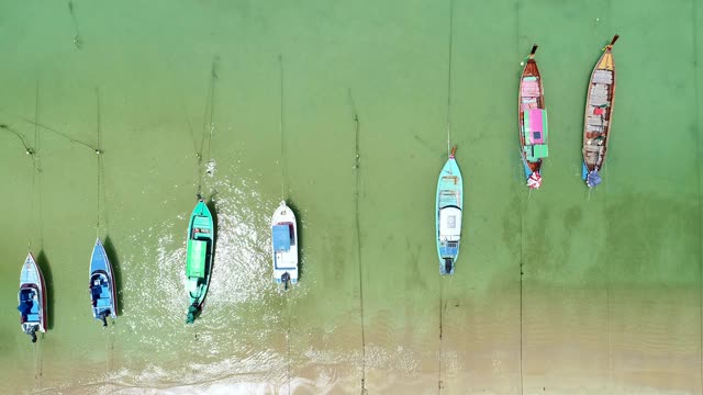 泰国传统的长尾船漂浮在翠绿的热带浅海中，清澈的海水在普吉岛拉威海滩视频素材