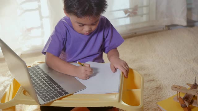 一个男孩在家里用笔记本电脑在线学习视频素材