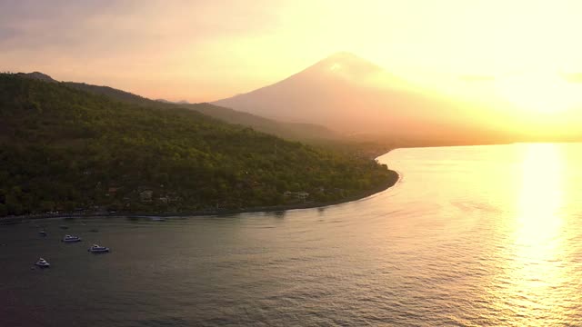 阿贡火山或阿贡火山在阿米德海滩在巴厘岛，印度尼西亚。美丽的日落和小雾的海滩。4 k鸟瞰图视频素材