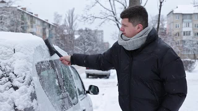 一场大雪过后，司机把车上的积雪清理干净。视频素材