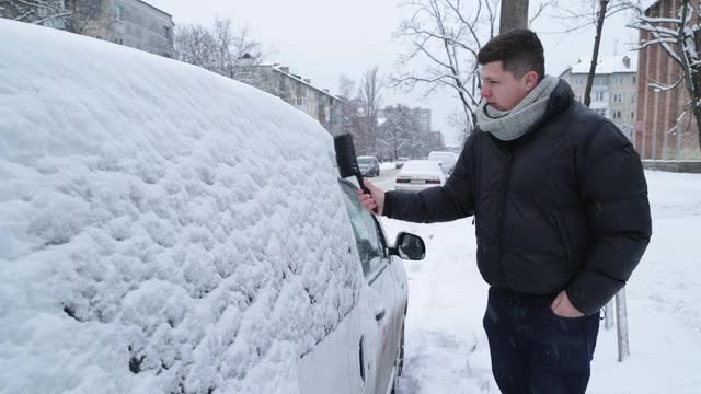 一场大雪过后，司机把车上的积雪清理干净。视频素材