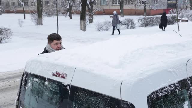 一场大雪过后，司机把车上的积雪清理干净。视频素材