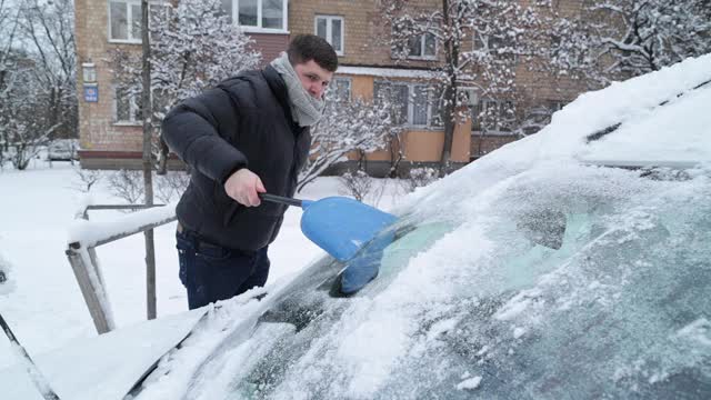 一场大雪过后，司机把车上的积雪清理干净。视频素材