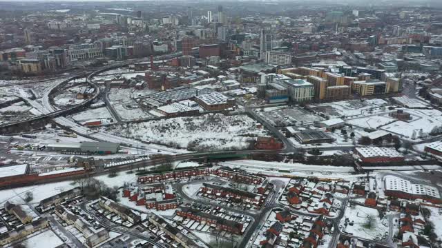 英国利兹市一个下雪天的航拍镜头，显示冬天比斯顿村一排排屋顶被雪覆盖的排屋视频素材