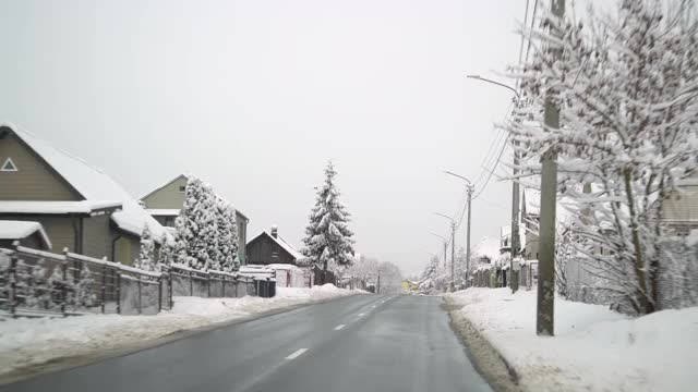 暴风雪过后，汽车行驶在乡间小路上。美丽的雪树，屋顶和冬天的风景。视频素材