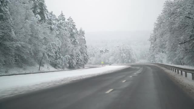 在暴风雪后的道路上驾驶汽车。美丽的雪树和冬天的风景。视频素材