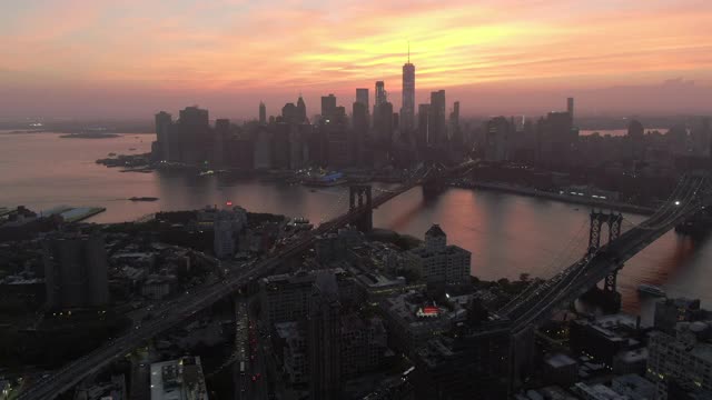 空中平移拍摄城市东河上的桥梁对天空，无人机在日落时飞过现代建筑-纽约市，纽约视频素材