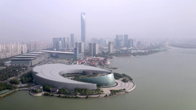 在阳光明媚的日子里，无人机在城市上空飞行，拍摄苏州文化艺术中心金鸡湖视频素材