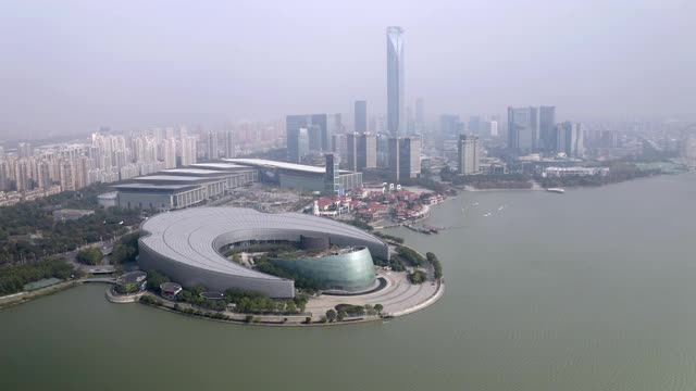 在阳光明媚的日子里，无人机在城市上空飞行，拍摄金鸡湖旁的苏州文化艺术中心视频素材