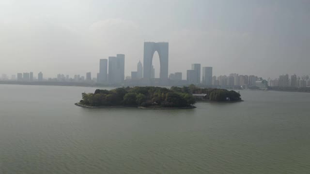 航拍金鸡湖上的岛屿对着建筑物，无人机向前上升对着天空的城市景观-苏州，中国视频素材