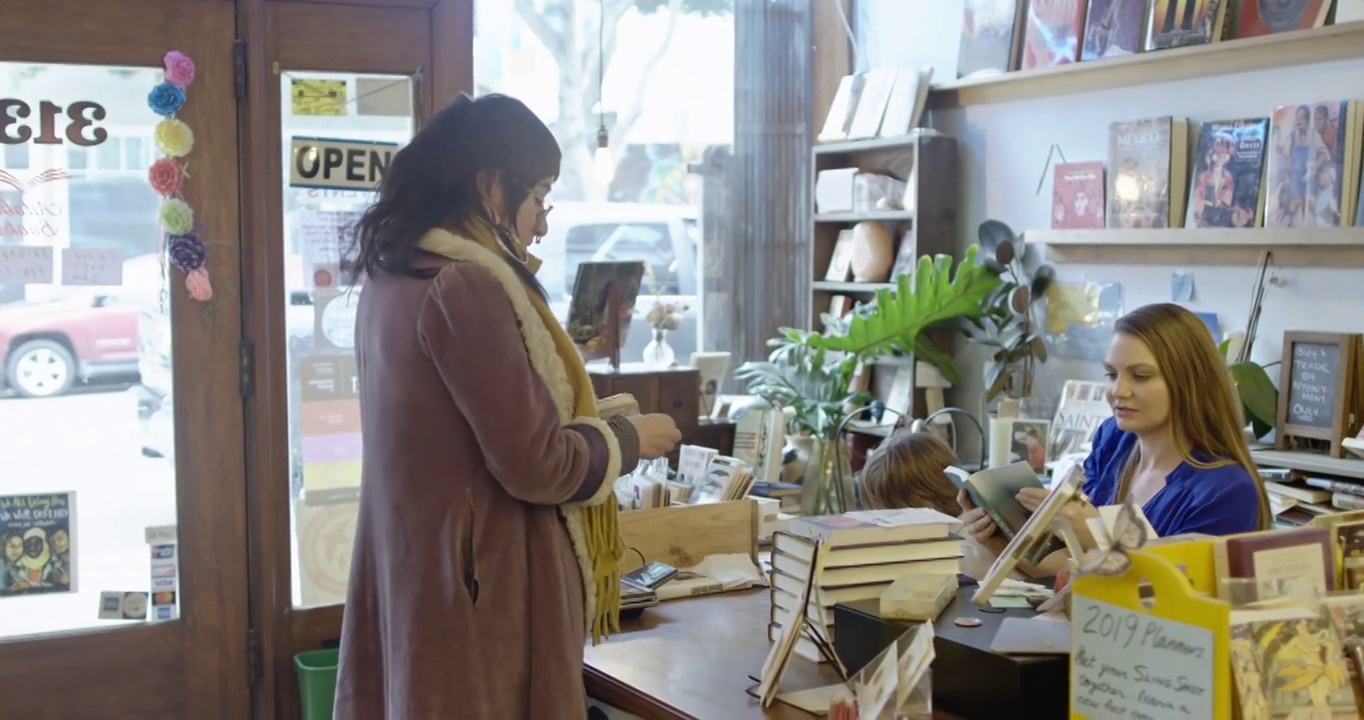 一个女人在书店里买书，妈妈把孩子放在腿上视频素材