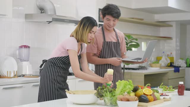 夫妻俩在家里一起在厨房做饭蔬菜沙拉视频素材