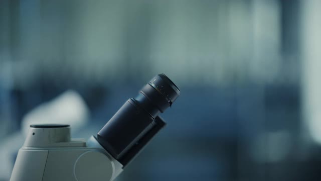 微距镜头的一个女科学家在面罩和护目镜看显微镜。在现代实验室中使用技术设备研究分子样本的女性微生物学家。视频素材