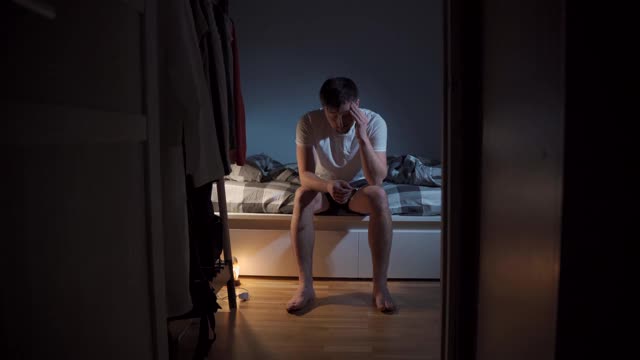 睡眠控制。男人在卧室遭受失眠，安眠药。压力、抑郁和睡眠问题。病男在床上吃药。悲伤的抑郁症患者在服药，有问题。视频素材