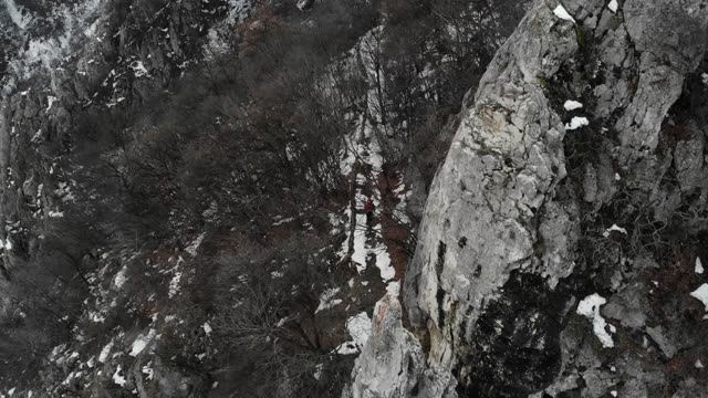 探险家在山顶，用无人机拍摄4k视频。这位登山者穿过一座山脉——冬季的风景视频素材画面1