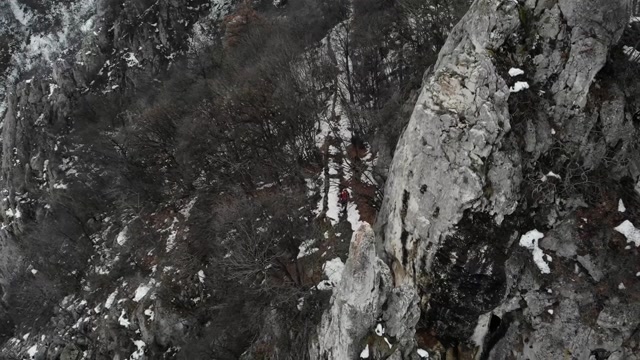探险家在山顶，用无人机拍摄4k视频。这位登山者穿过一座山脉——冬季的风景视频素材画面3