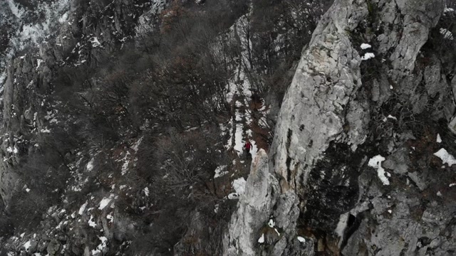 探险家在山顶，用无人机拍摄4k视频。这位登山者穿过一座山脉——冬季的风景视频素材画面4