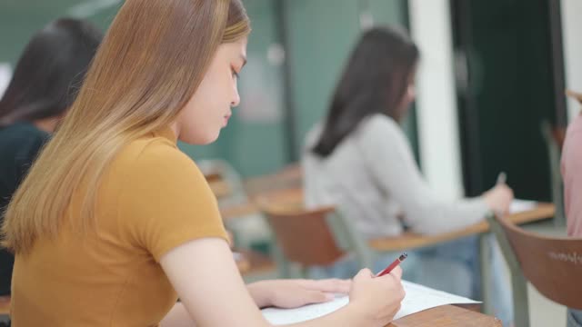 学生们坐在大学教室里的课桌前考试。视频素材