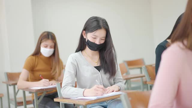 学生们坐在大学教室里的课桌前考试。视频素材