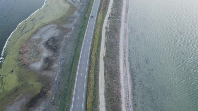 汽车在大湖泊之间的公路上行驶的鸟瞰图。视频素材