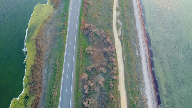 日落时分，一辆汽车在海边公路上行驶的鸟瞰图。视频素材